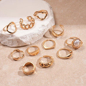 Macro shot of a 10-piece gold geometric ring set on marble, featuring textured details