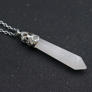 Detail view of white crystal hexagonal pendant with silver hollow metal cap on dark surface