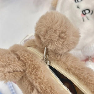Close-up of soft brown plush pencil case with zipper closure and cute pom-pom ears