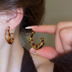 Detailed close-up of retro leopard resin C-shape hoop earring worn on a model ear