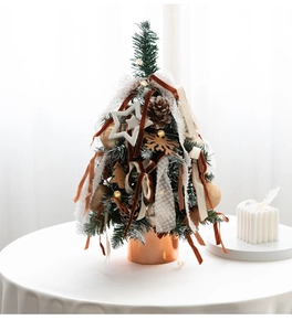 Close-up of mini Christmas tree with velvet ribbons and LED lights in bronze pot