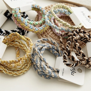 Elastici per capelli intrecciati in colori pastello su sfondo di rattan con cartellino