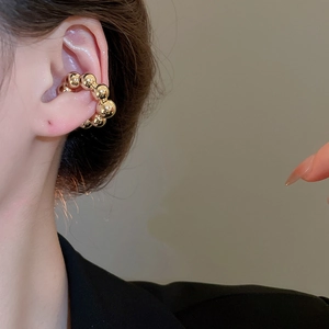 Vista macro dettagliata di un ear cuff a sfere dorate lucide sull'orecchio