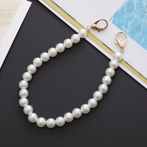 Detail of elegant white faux pearl strap with gold lobster clasps on a magazine background