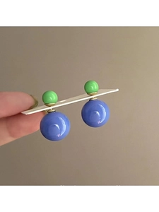 Détail des boucles d'oreilles asymétriques à double perle verte et violet bleu à fini brillant