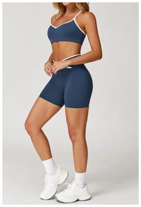 Detail van high-waist yogashorts en V-hals bh met witte contrastbies in marineblauw