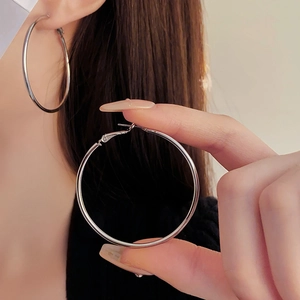 Close-up of minimalist large silver hoop earrings worn by a model in natural light