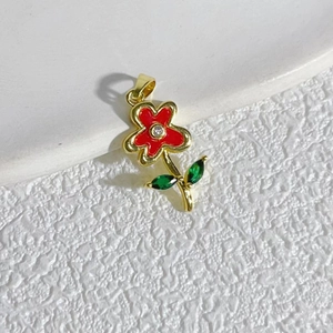 Minimalist gold flower pendant with red zircon petals and green leaves on white stone
