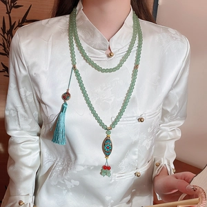 Detail of vintage beaded necklace with light green beads and blue tassel pendant