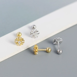 Macro view of gold and silver flower stud earrings with sparkling crystals and screw backs