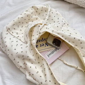 Detail view of corduroy tote bag with brown floral pattern on beige fabric surface