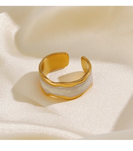 Detail of gold-plated wavy ring with white marble enamel on soft silk background