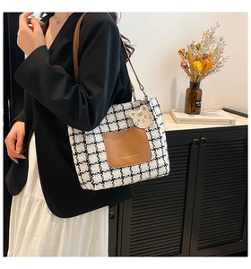 Detail of checkered tote bag with brown leather pocket and cute white tiger charm