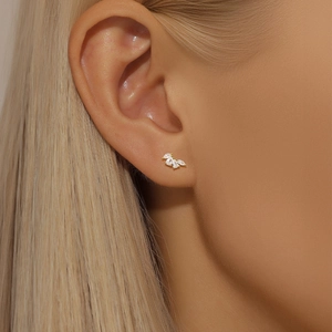Close-up of gold-plated leaf studs with three marquise-cut zircons worn on ear