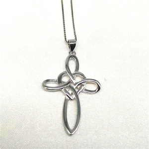Detail of silver S925 Celtic cross heart pendant on white textured fabric background