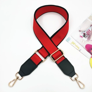 Detail of red and black canvas bag strap with golden metal swivel hooks and PU leather