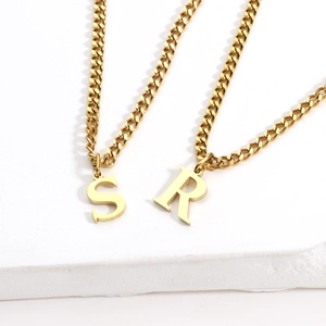 Detail view of 18K gold plated S and R initial pendants on a classic Cuban link chain
