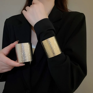 Detailed close-up of textured gold and silver irregular hammered metal cuff bracelets