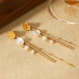 Detailed shot of gold tassel earrings with hanging pearls and glittering rhinestone chains
