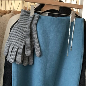 Guantes de punto de lana gris en percha de madera con elegante conjunto azul y perlas