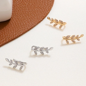 Detailed macro view of leaf cuff earrings in gold and silver with cubic zirconia stones