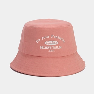 Detailed close-up of pink canvas bucket hat featuring white printed letters and fine stitching