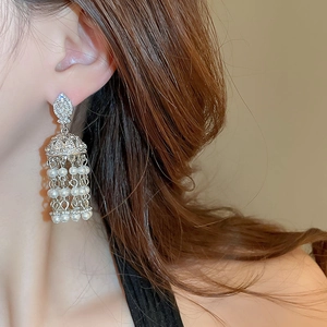 Gros plan sur des boucles d'oreilles pendantes en perles et strass au style ethnique chic