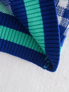 Close-up of the ribbed cuff showing blue and green striped knit textures on the sweater