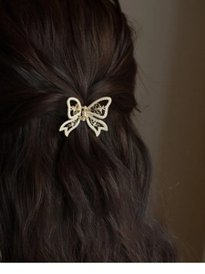 Elegant gold butterfly hair claw clip with white pearls on wavy brown hair
