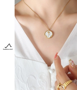 Detail of gold rose pendant necklace and stainless steel clasp on a model's neck