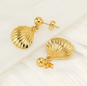 Macro shot of gold shell-shaped earrings showing fine texture on silk background