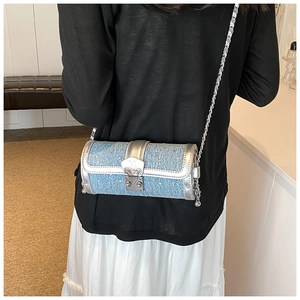 Detail of denim cylinder bag with silver chain and rhinestone accents on model