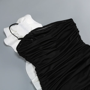 Detail of black strapless evening dress with white ruffled flowers and pleated fabric