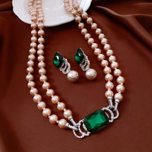 Macro view of vintage style emerald and champagne pearl necklace and earring jewelry set