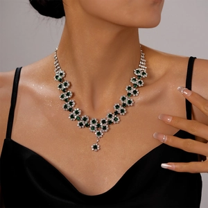 Detail of luxury silver necklace with green emerald gemstones and sparkling zircon flowers