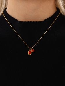 Detail einer Goldperlenkette mit roten ovalen und tropfenförmigen Zirkonia-Anhängern
