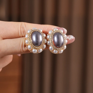 Detailed view of vintage gold earrings featuring grey pearl center and zircon crystals