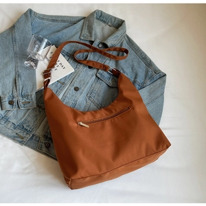 Close-up of brown nylon tote bag with silver metal zippers on denim jacket