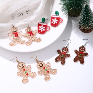 Detail view of gingerbread man and red snowflake cup earrings with sparkling glitter finish