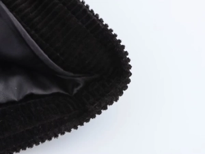 Gros plan sur la texture du velours côtelé noir et la doublure lisse de cet ensemble