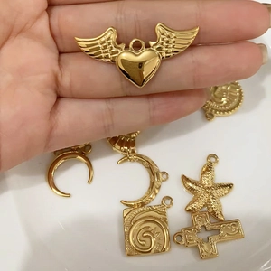 Close-up of assorted gold titanium steel pendants including heart wings and starfish shapes