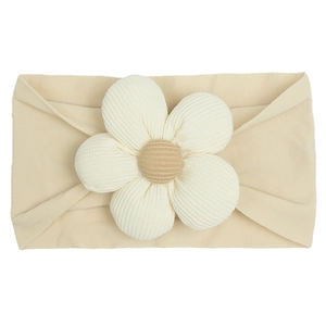 Detailed top view of a soft beige baby nylon headband featuring a large white 3D flower