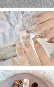 Close-up of elegant gold cross nail charms with rhinestones on nude manicure nails