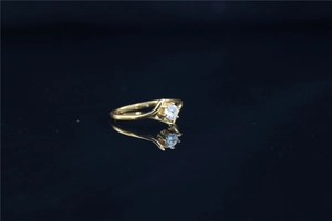 Macro view of six-prong setting with clear moissanite on a gold wave band ring