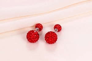 Detail of red crystal pave ball earrings in S925 silver on beige soft fabric