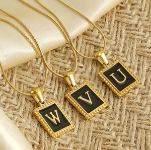 Detail of 18K gold-plated square initial pendants on snake chains with black enamel