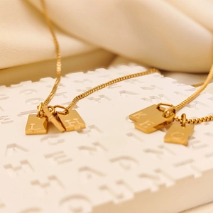 Macro shot of gold square initial pendants with letters engraved on elegant box chains