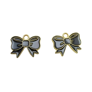 Detail of pair of black enamel bow pendants with gold metal edges for DIY jewelry making