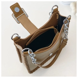 Detail of brown leather tote bag with woven edges, chain handle and inner zip compartment