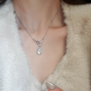 Detailed view of hulu pendant necklace with white gemstone and pavé stones on a model
